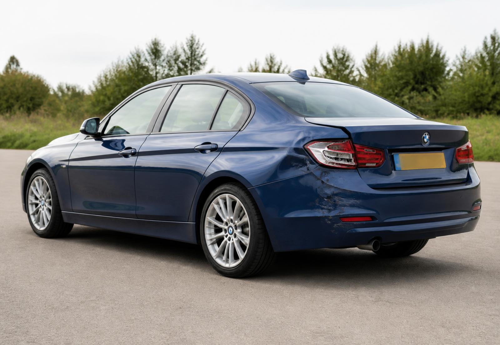 Dark blue saloon with rear-corner accident damage being assessed
